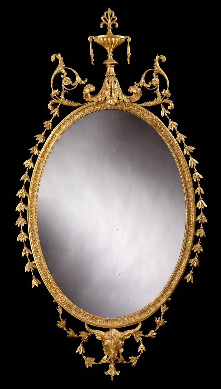 A fine and substantial mirror in the Robert Adam manner.

Primarily giltwood, and having an the elliptical mirror plate housed within a continuous band of stiff leaf moulding, enclosing a running pearl band, with a striking and large ram’s head