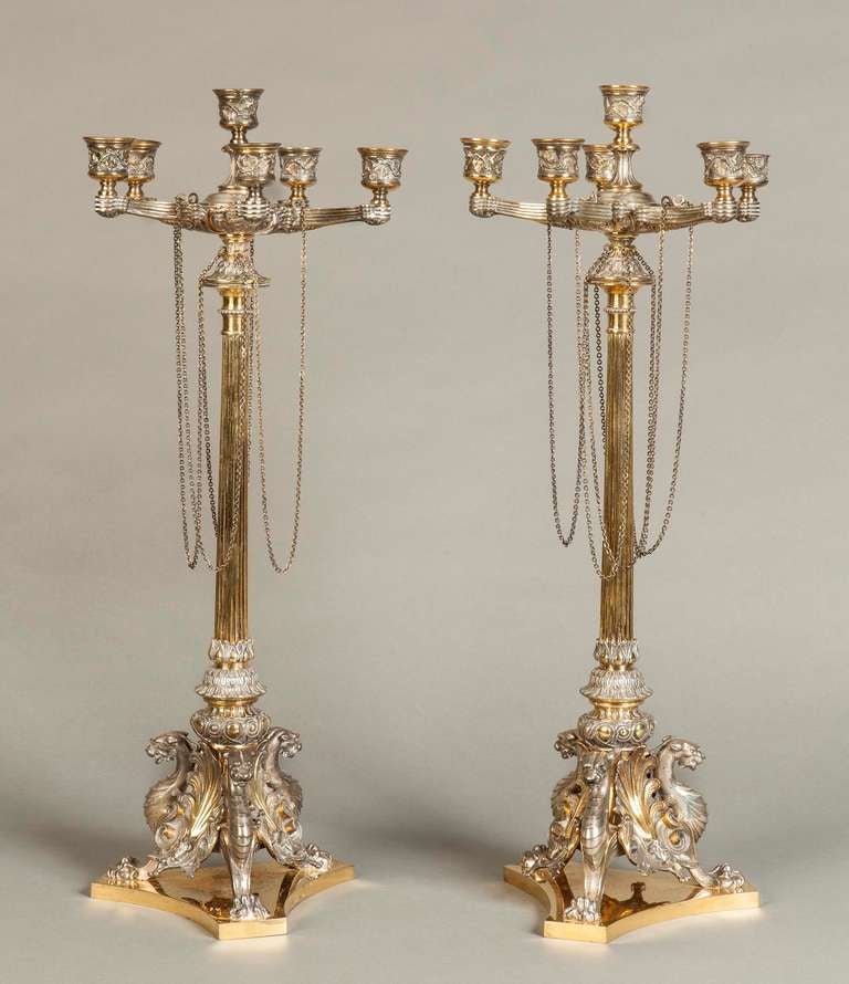 Each with six curved candle branches, the reeded column raised on a foliate shell and griffin tripartite base and decorated with hanging chains.
Bearing the marks for the year 1865.

Literature:
Elkington and Company, formed by the brothers George