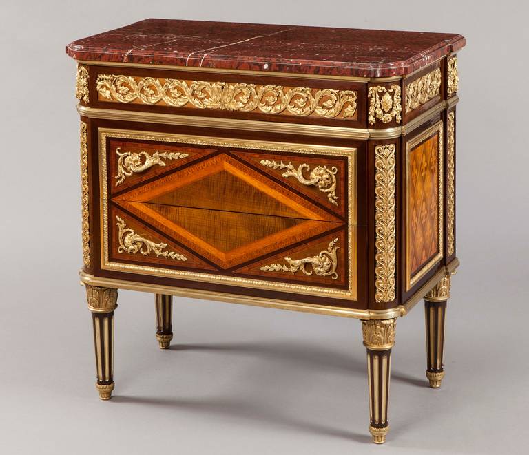 A Diminutive Commode in the Louis XVI Manner After the original by J.F Leleu, By Millet of Paris

Constructed in purpleheart wood, amaranth and kingwood, and dressed with very fine ormolu mounts; rising from gently tapering columnar legs, shod at