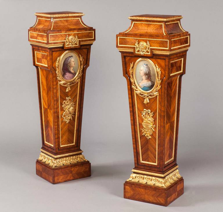 A Pair of Pedestals in the Louis XVI Manner

Constructed in kingwood, and dressed with ormolu gilt bronze mounts; rising from stepped rectangular plinths, dressed with bronze stiff leaf ormolu mounts, the columns of tapered and shouldered form,