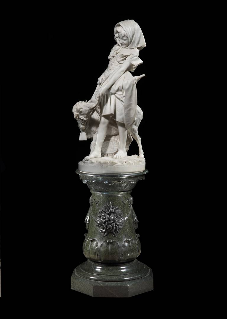 Carved in a virtuoso manner and ability, the white Carrara statuary marble, of monumental size, depicts ‘Mary’, bonneted, and dressed in the style of an Italian farmer’s daughter, happily laughing at her lamb nibbling at the leaves of cavolo nero