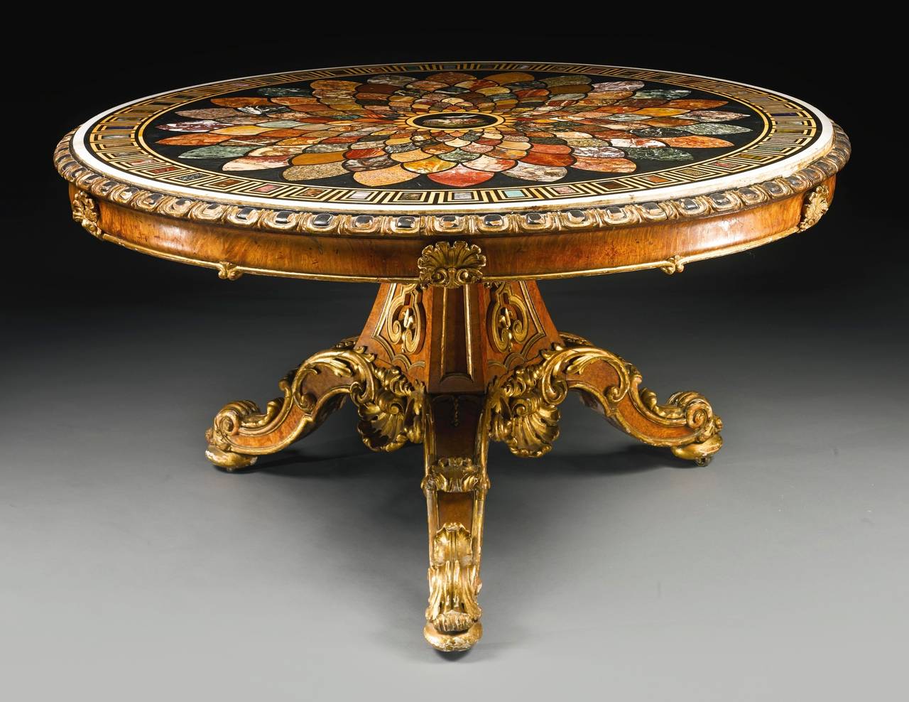 Constructed in Burr Walnut, in part ebonized and parcel gilt, with a specimen marble and micromosaic platform, probably by Alfonso Cavamelli of Rome: rising from a tripartite base, the legs of scrolled and hipped form, boldly carved with ‘C’