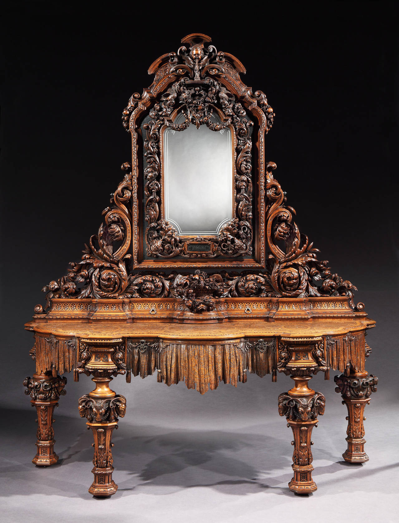Constructed from fruitwood, comprehensively carved with exquisite skill and artistry; supported on removable legs, for the ease and safety of transportation, which screw into the serpentine form engraved platform, having drawers in the frieze,