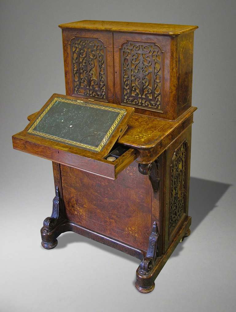 Constructed in Circassian walnut, with line and marquetry inlays; rising from turned oblate bun feet; the lower section housing a hinged door with fretwork panelling, opening to reveal four lemonwood faced graduated drawers with inset turned knobs;