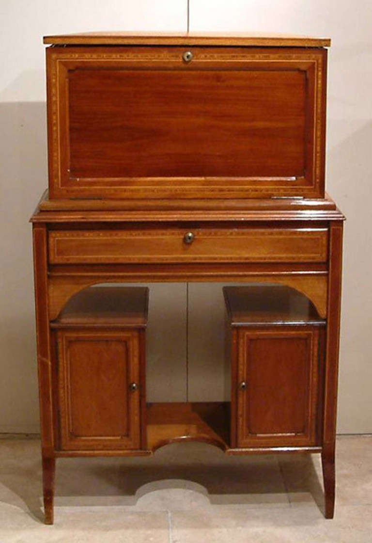 In Honduras mahogany, cross banded in satinwood, the drop flap upper section is removable, and sits on a base containing cupboards with mahogany lined interior drawers. The writing section is multi compartmented, with sections for stamps,