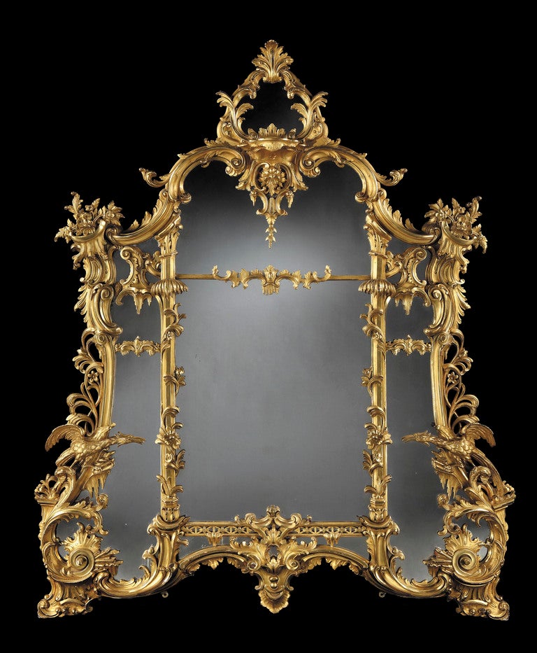 The well carved frame incorporating addorsed Ho Ho birds, ‘C’ scrolls, icicles, pierced trellising and foliates; of assymetrical form and housing a mercury backed mirror plate.