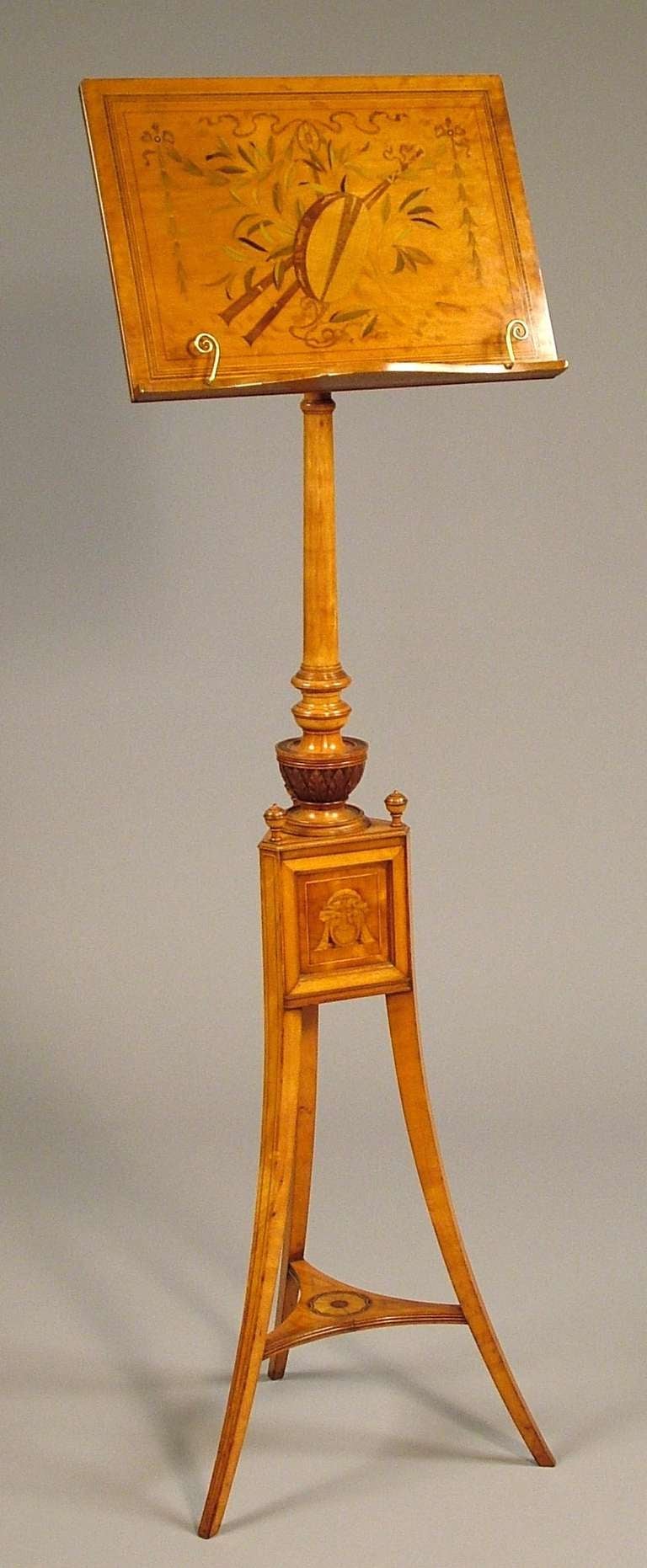 Constructed in Satinwood, extensively inlaid, the tripod footed base of outswept tapering form, with a patera inlaid platform, supporting a triangulated box centre, with masks inlaid, and knopped angles, the central column adjustable, the music