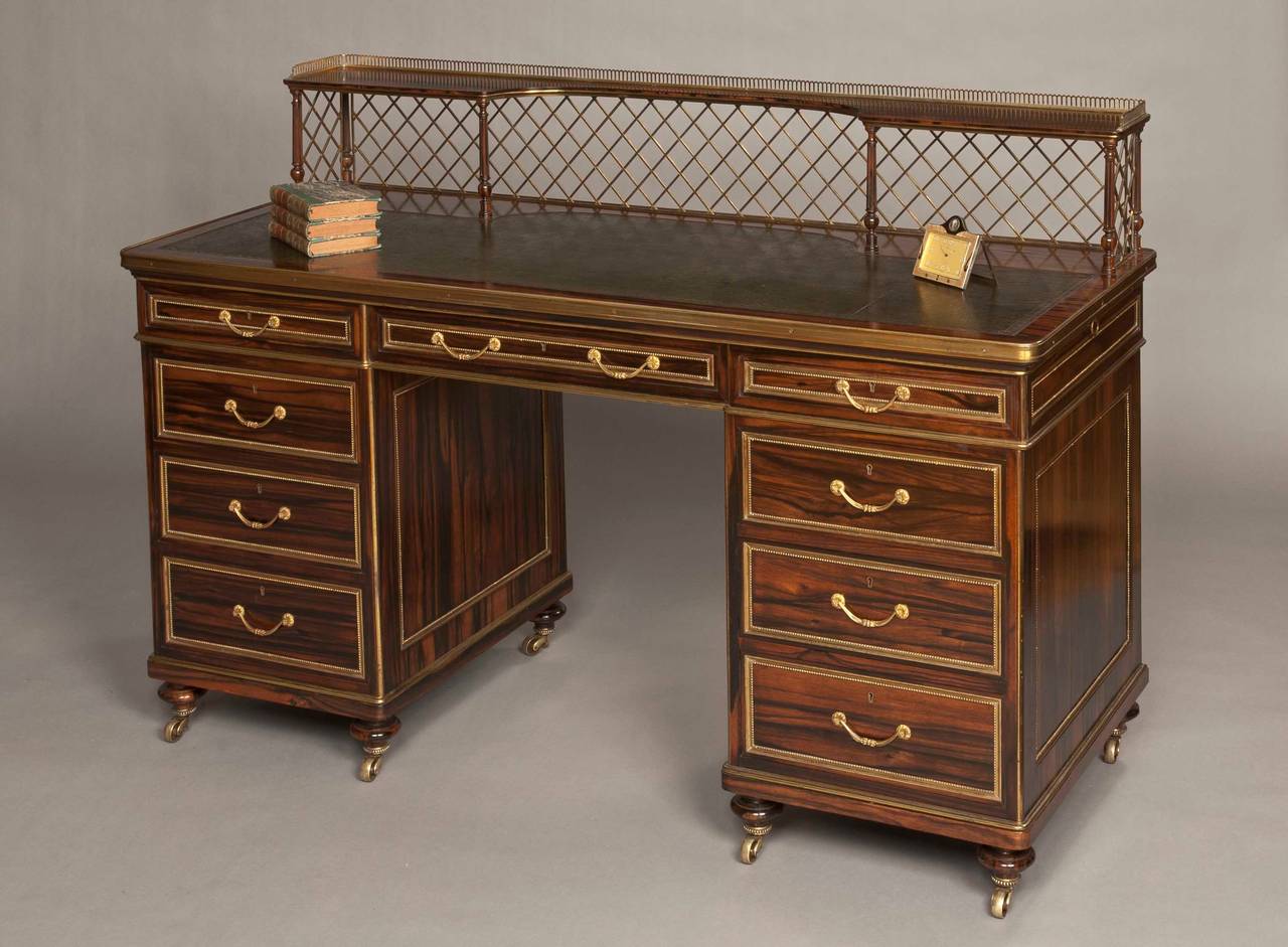 A very fine writing desk firmly attributed to Wright & Mansfield.

Constructed in coromandel with extensive gilt brass work fittings; rising from caster shod toupie feet, the two pedestals housing three lockable graduated drawers, with gilt brass