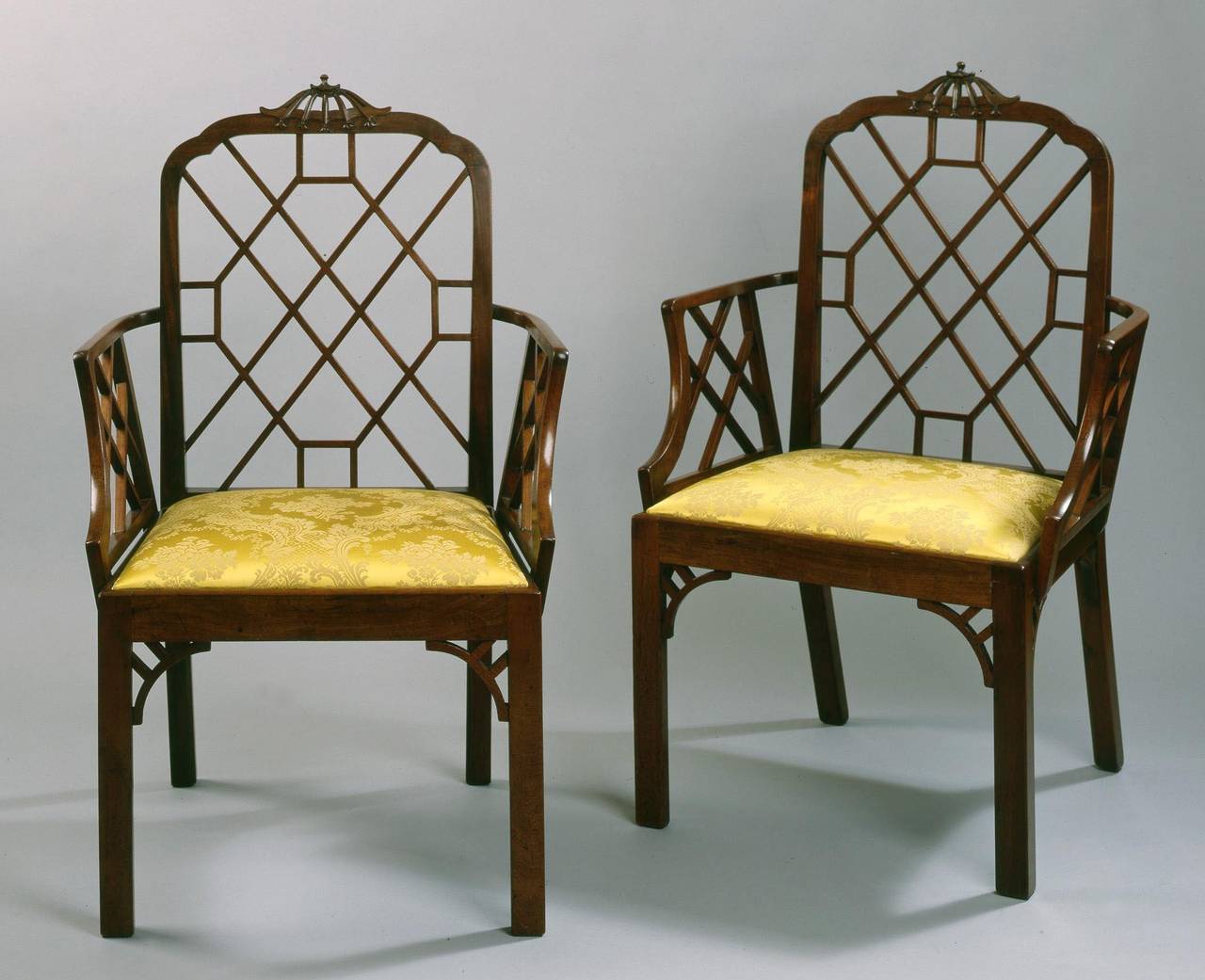 Constructed in mahogany, rising from chamfered square section front legs, decorated with ‘c’ scrolls: the lift out seat upholstered, the arms with lattice work, the back of a ‘spider web’ form, the top rail with a pagoda crest, Bellflowers pendant.