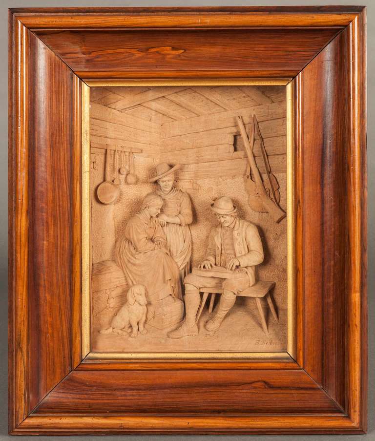 Finely carved in Limewood, and depicting a farmhouse interior, with two ladies and a dog being entertained by a musician plucking a zither. Signed by the artist lower right, and set in a walnut ogee frame.