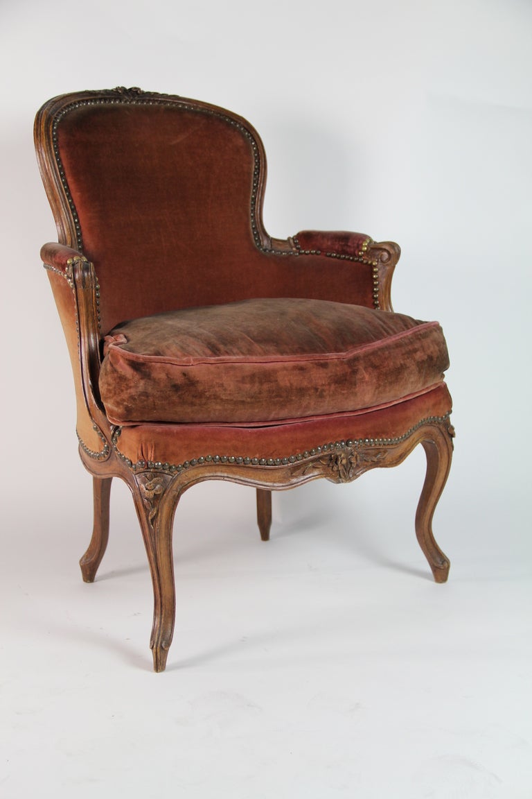 A carved walnut Louis XV style and period bergere with brown velvet upholster