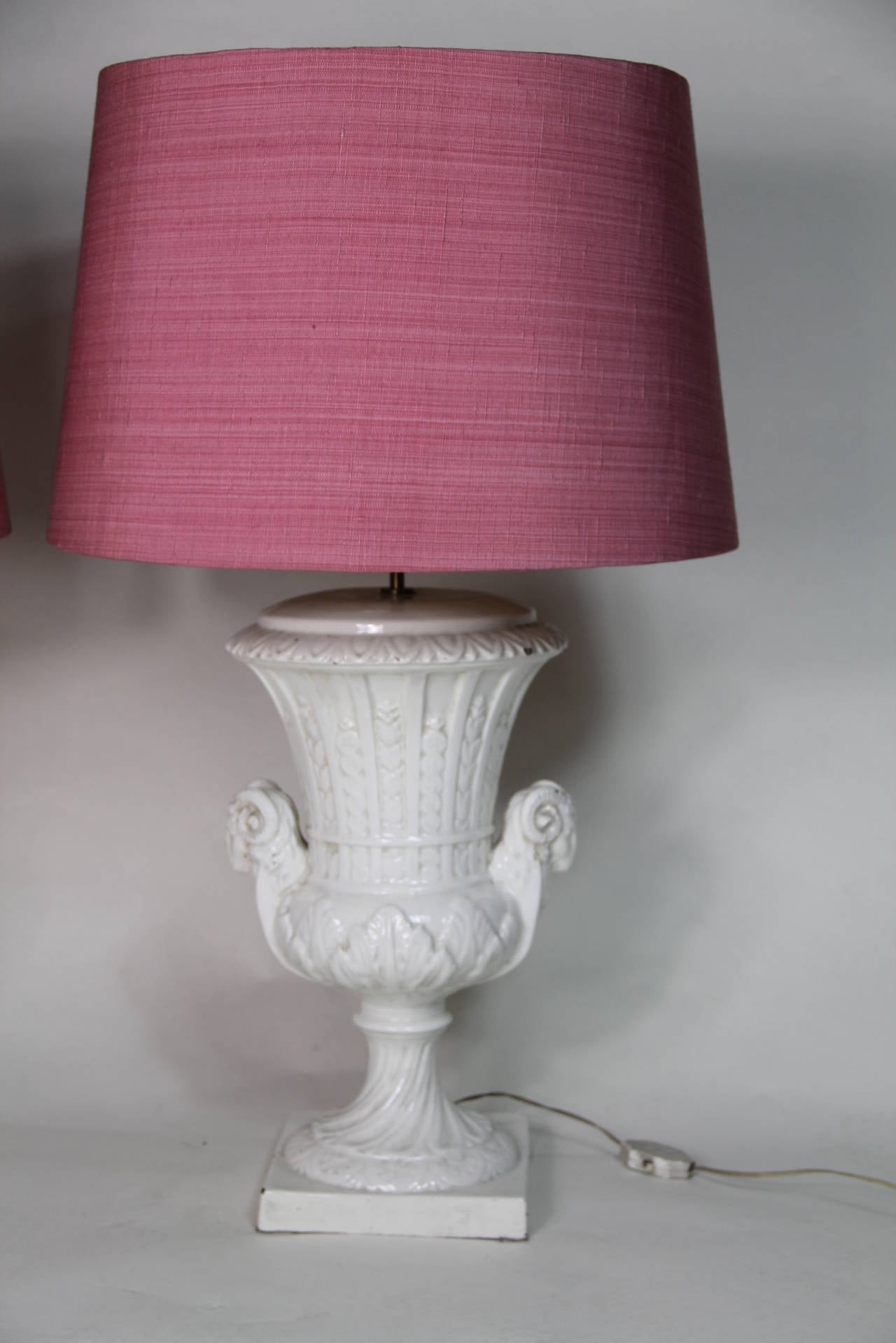 A pair of white glazed ceramic urns as table lamps with original pink silk shades