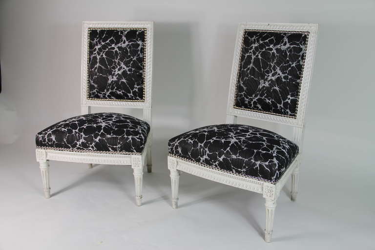 A pair of painted Louis XVI style low chairs upholstered in Rubelli fabric.