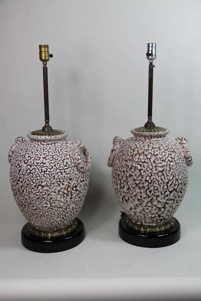 A pair of decorative white ceramic lamps on a brass and ebonized stand,