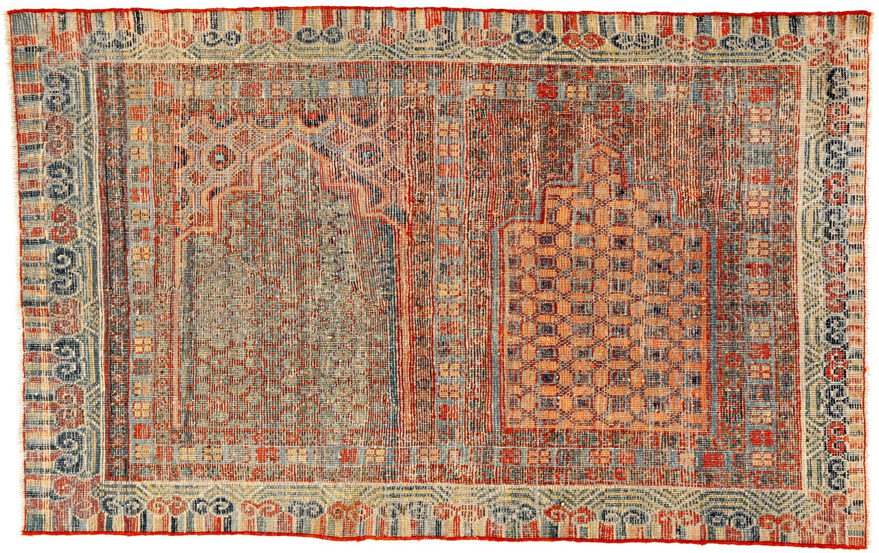 I don’t know of any other East Turkestan rug with only two niches, displayed here in a sort of yin yang. The outstanding palette, consisting of three shades of red, blue and green, is used with the mastery of an experienced weaver, imparting a