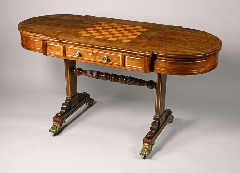 Regency rosewood and brass line inlaid games table. The sliding center section reverses to a chess board. When removed the well contains a backgammon board, circa 1815. Possibly by Gillows.