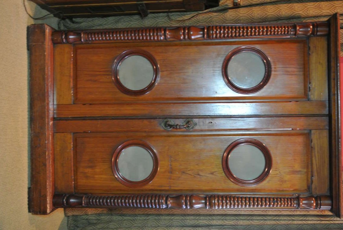 Cabinet fronted with a pair of doors, each with two porthole windows above a molded base. turned post corners.