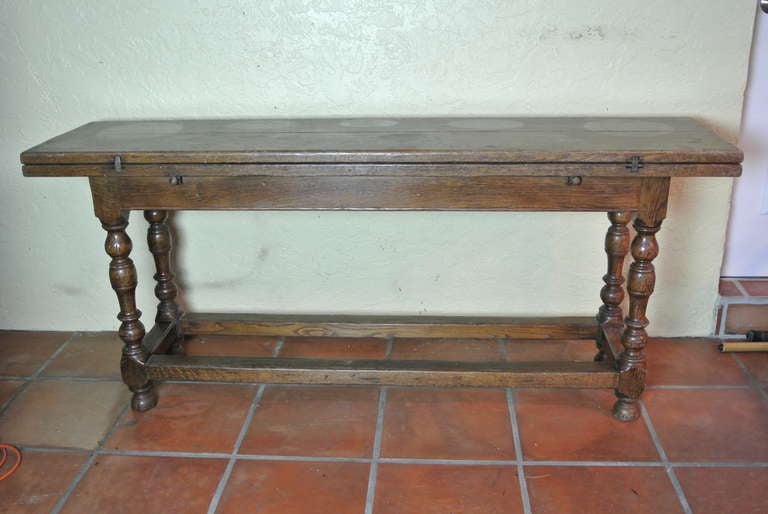 Wood fold out table doubles in width for use or can stay against wall as a serving table. This table has fine natural patina from years of use. There are inlaid ground steel 