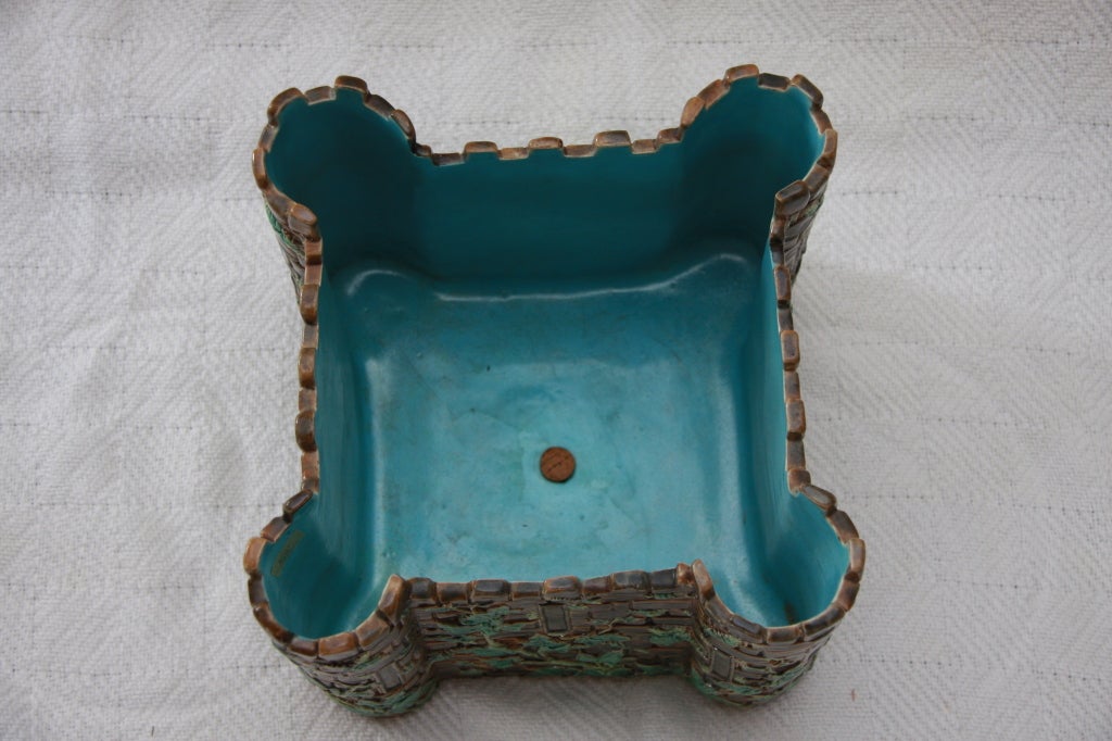 Geoge Jones majolica castle-shaped jardiniere, circa 1880.Modelled as a square brown stone castle, the exterior molded with creeping ivy and ferns, the interior glazed in turquoise. Black painted shape number 3357, drain hole in base added.  Also