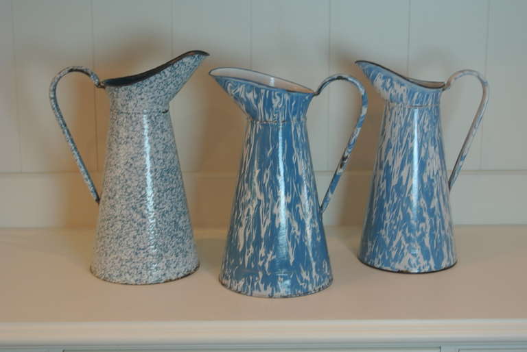 Blue and white enameled tin milk pitchers with handles.