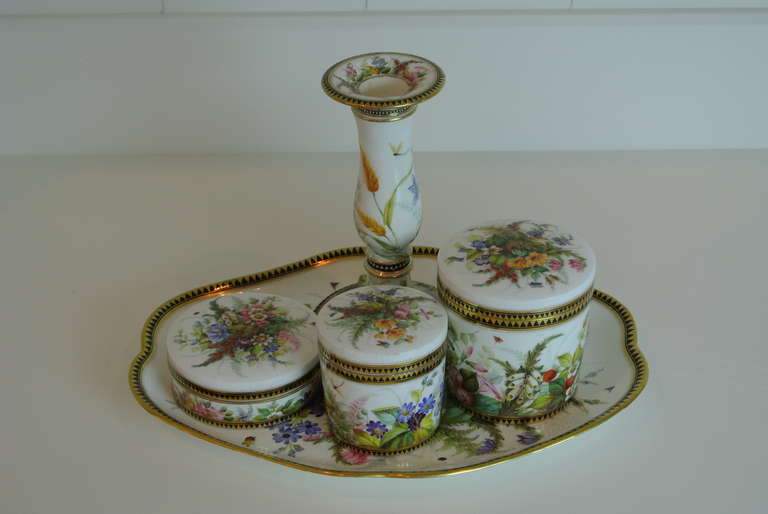 Elegant dresser set consisting of three covered jars, candle stick and tray with polychrome and gilt decoration.