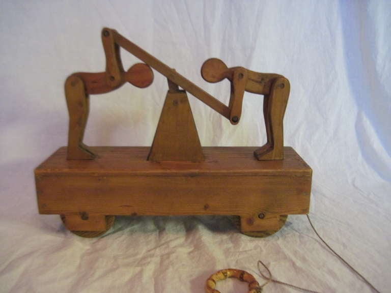 Fun antique pull toy that is cleverly constructed as two men on hand truck. Up and down motion when pulled.