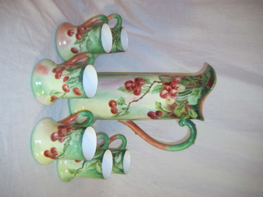 Beautiful complete set of six mugs with handles. This set includes the tall serving pitcher, all in a lush ripe cherry motif on a washed green ground. marked Limoges, France. Mugs approximately 5