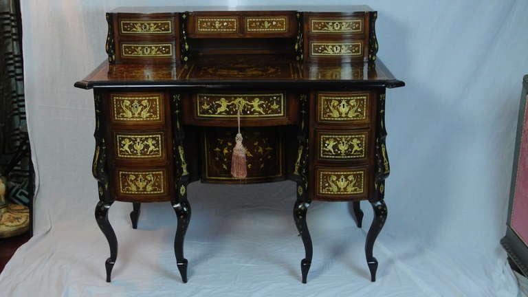 Inlaid marquetry writing table of fine quality. This beautiful example glows with antique ivory inlays of a playful nature. Figures leap through a fiery rosewood surface. Ebony corners and edges contain panels, top and drawers. There are fourteen