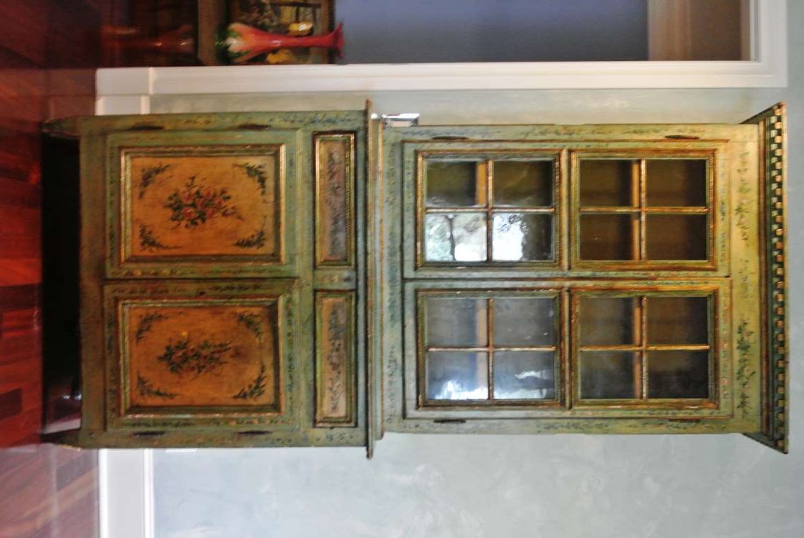 Intricately painted apple green antique linen press from Howard Kaplan. Glazed doors on upper cabinet open to an interior lined in antique deep gold velvet.
