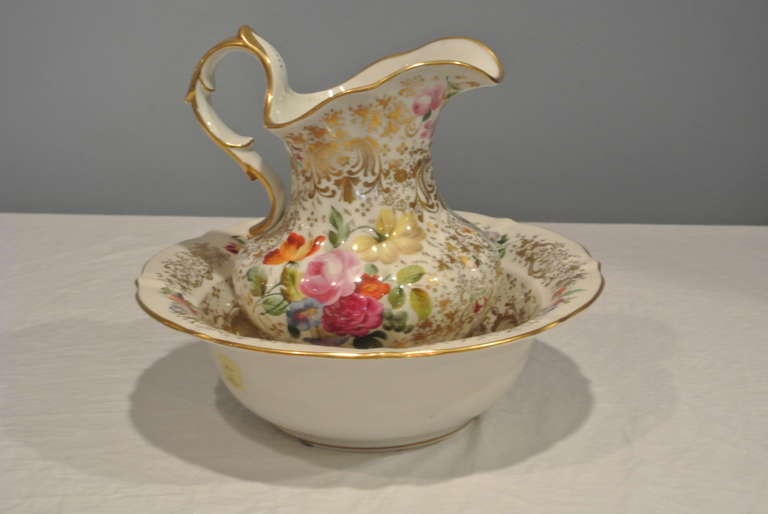 Decorated pitcher and basin decorated with a areas of poly chrome floral groupings surrounded by bright gold filigree.