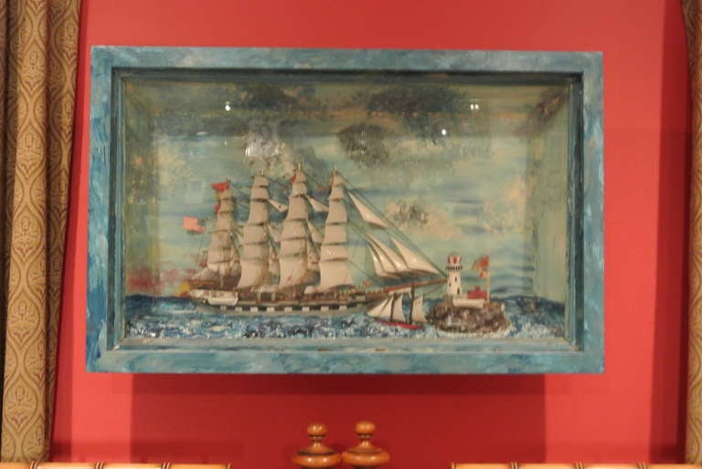 Really great and original folk art diorama with nautical theme. This diorama is all painted out in a variegated blue water and sky treatment. There is much fine and interesting detail inside shadow box such as two american flags, lifeboat, ship,