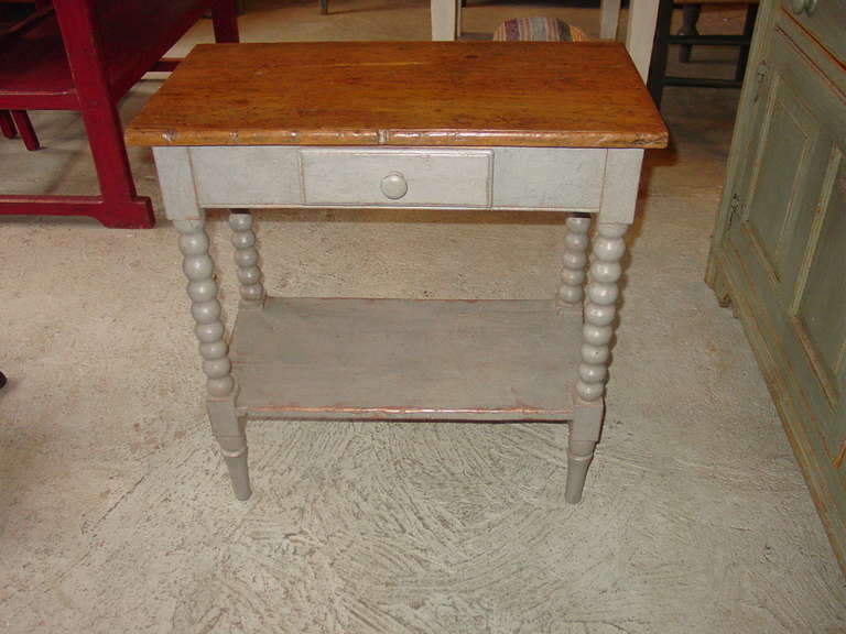 A petite work table with spool turned legs, shelf and one drawer.