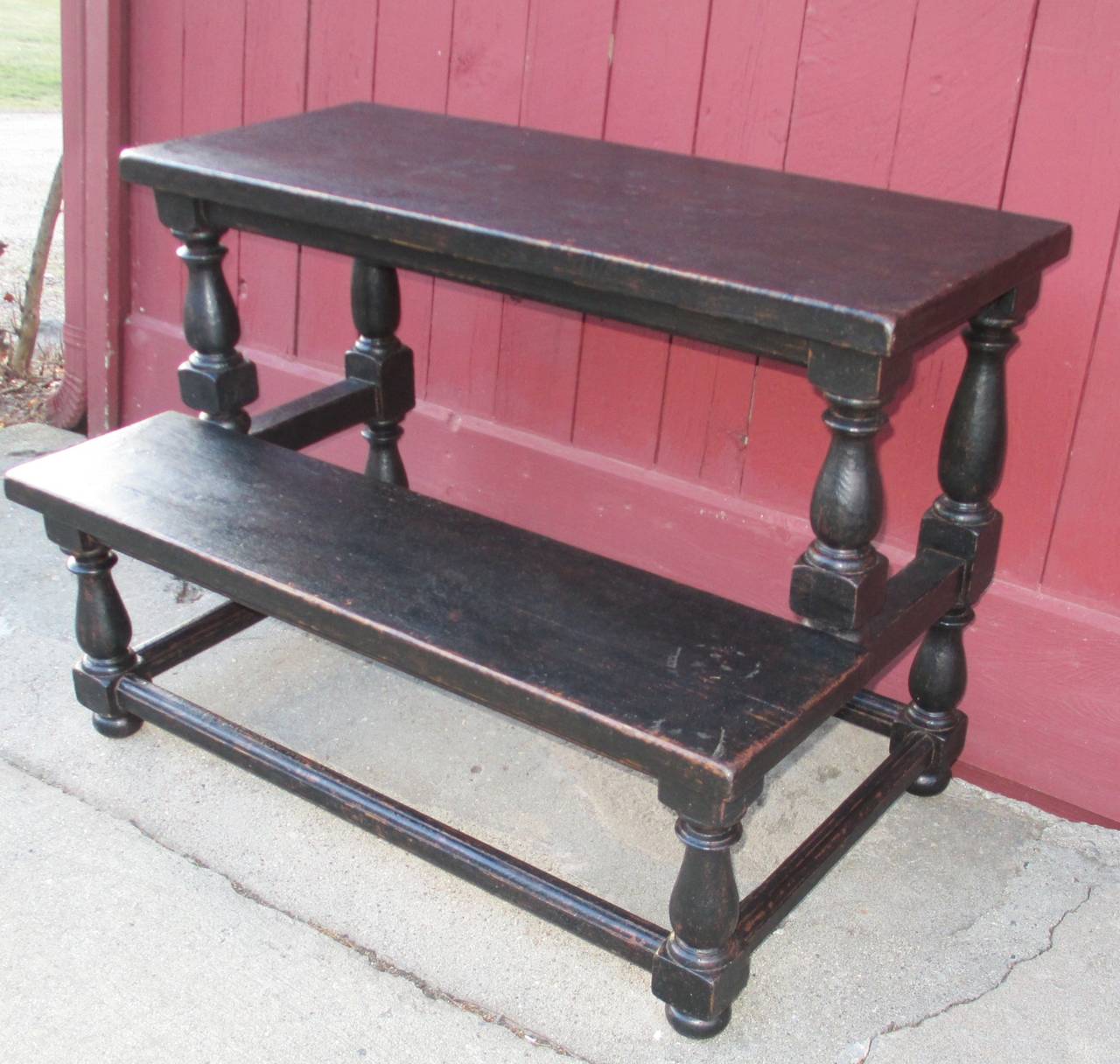 Black painted plant stand with wide shelf and turned legs.