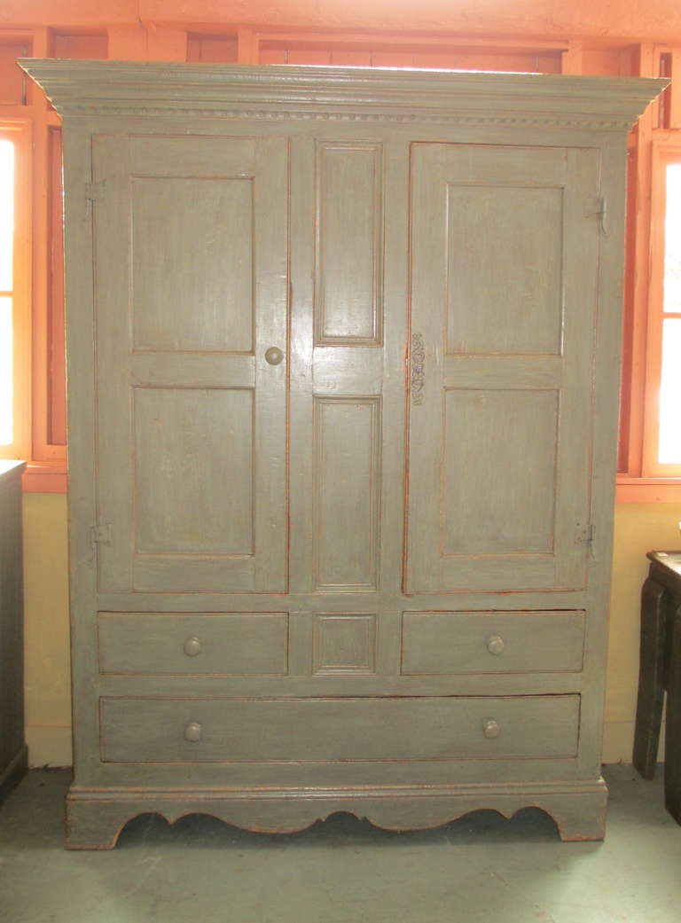 Armoire with three drawers and decorative moldings and cornice