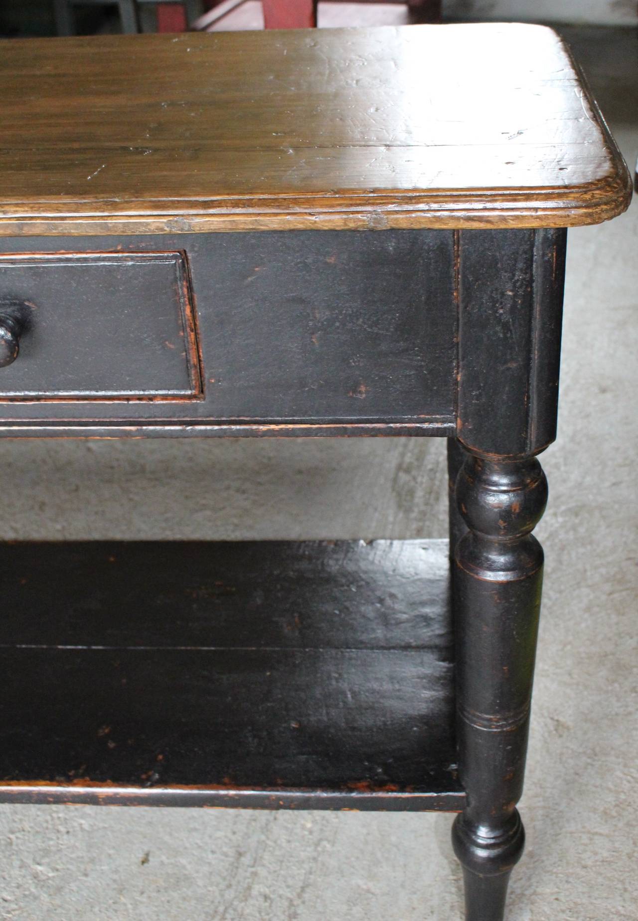 A sideboard table with turned legs, two drawers and shelf.