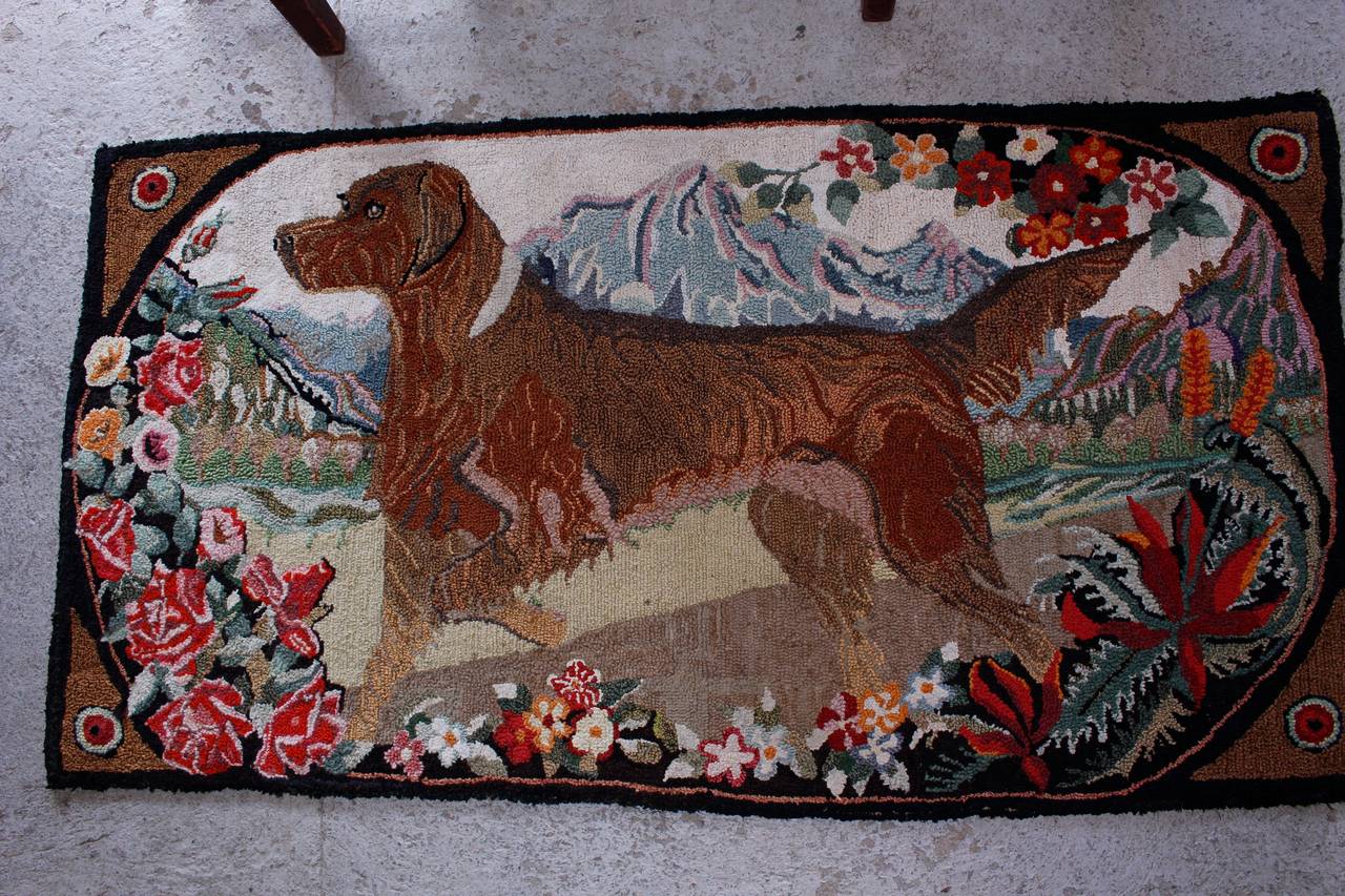 A folky handmade hooked rug of a dog surrounded bold colored flowers.