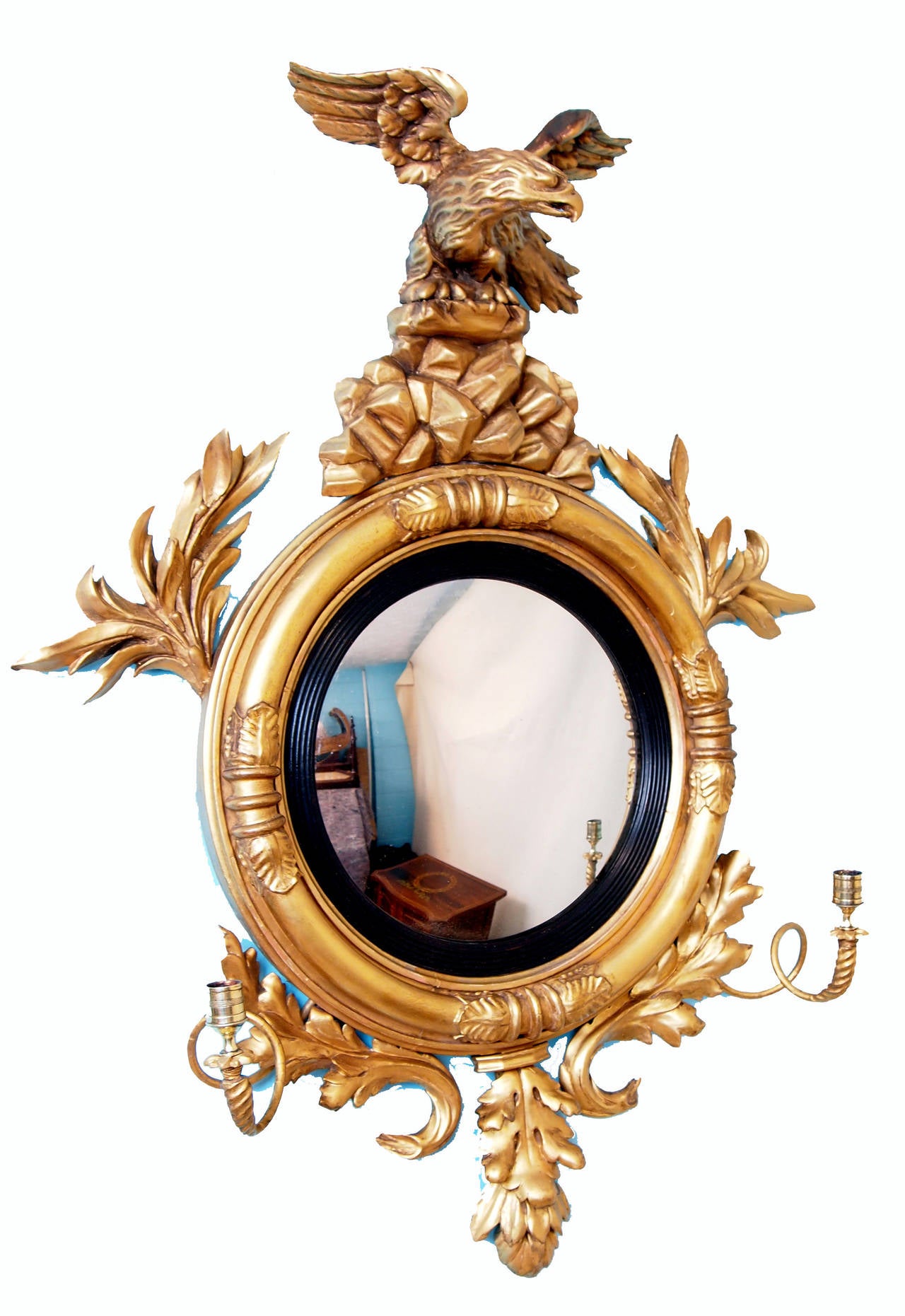 A Delightful Regency Period Gilt Convex Mirror Of Unusually 
Small Proportions Having Well Carved Eagle On Rocks Surmounted 
To Top And Carved Foliage Flanked By Original Candle Sconces 
To Bottom