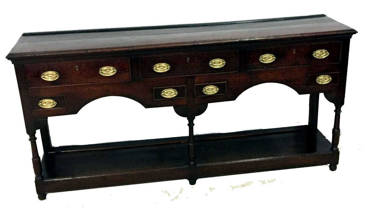 A Very Attractive Early 19th Century Oak Dresser Base Having Well 
Figured Top Above Three Drawers And Two Knife Drawers To 
Elegant Shaped Frieze Raised On Turned Upright Supports With 
Original Potboard Below
