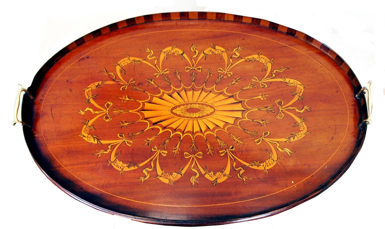 A very good quality late 19th century mahogany
the oval tray having profuse marquetry inlaid decoration
and chequered gallery raised on later mahogany
square leg stand.