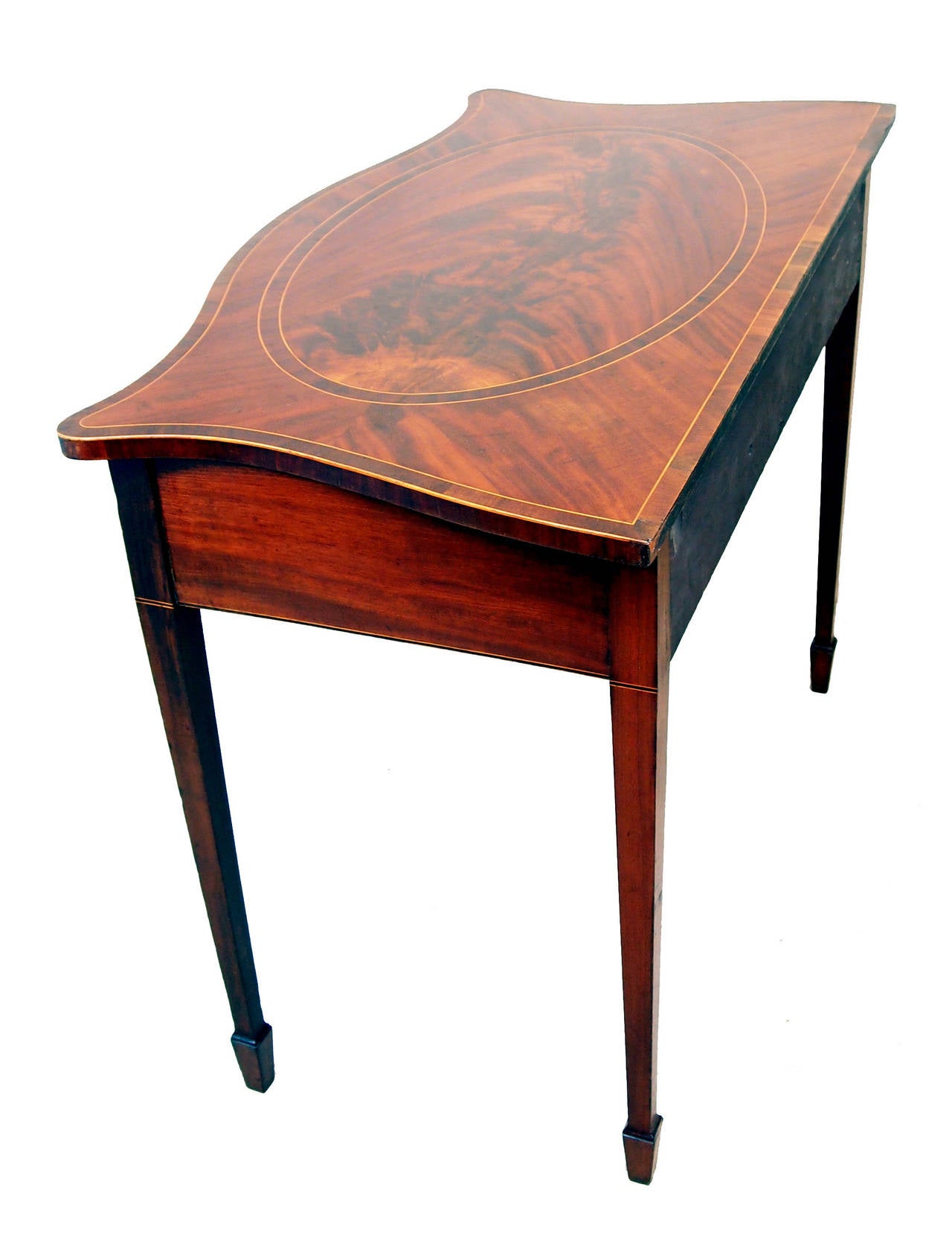 A Very Good Quality Late 18th Century Mahogany Serpentine Side 
Table Having Superbly Figured Top With Central Banded Oval Panel 
Above Cross Banded And Inlaid Frieze Drawer Raised On Elegant 
Square Tapered Legs Terminating On Spade Feet