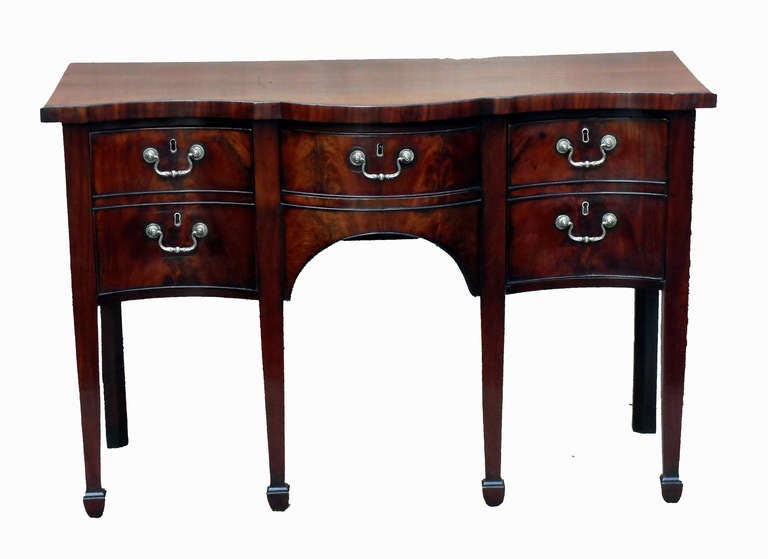 A George III period serpentine sideboard of diminutive proportion having superb flame mahogany veneers standing on square tapered legs.
