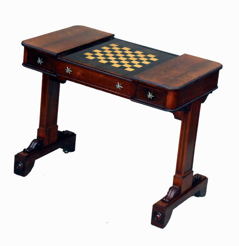 A Superb Quality Regency Rosewood Library Games 
Table Having Adjustable Sliding Top To Reveal 
Backgammon & Chess Boards Standing On Tablet 
End Supports With Carved Scroll Decoration