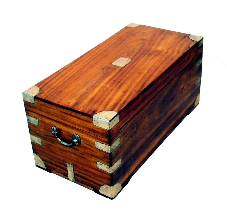 A mid-19th century camphor wood military campaign trunk having well figured lift up lid and original brass bound decoration and carrying handles.
