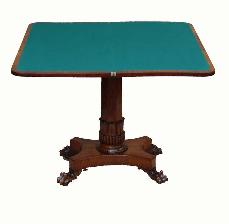 A William IV Period Figured Oak Card Table Of 
Exceptional Quality Having Fold Over Swivel 
Crossbanded Top With Rosewood Inlay Decoration 
Supported By Carved Central Column Above Plateau Base With Carved Paw Feet