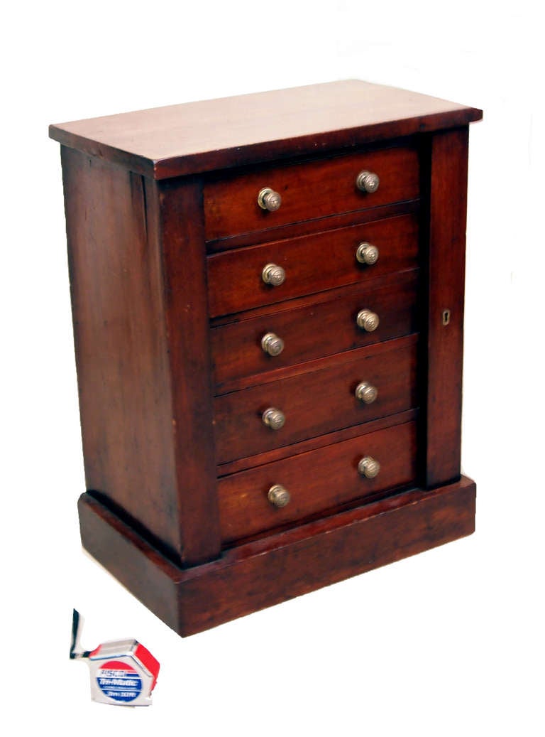 A delightful mid-19th century mahogany childs size Wellington 
chest of five long drawers with locking pilaster raised on 
original plinth base.