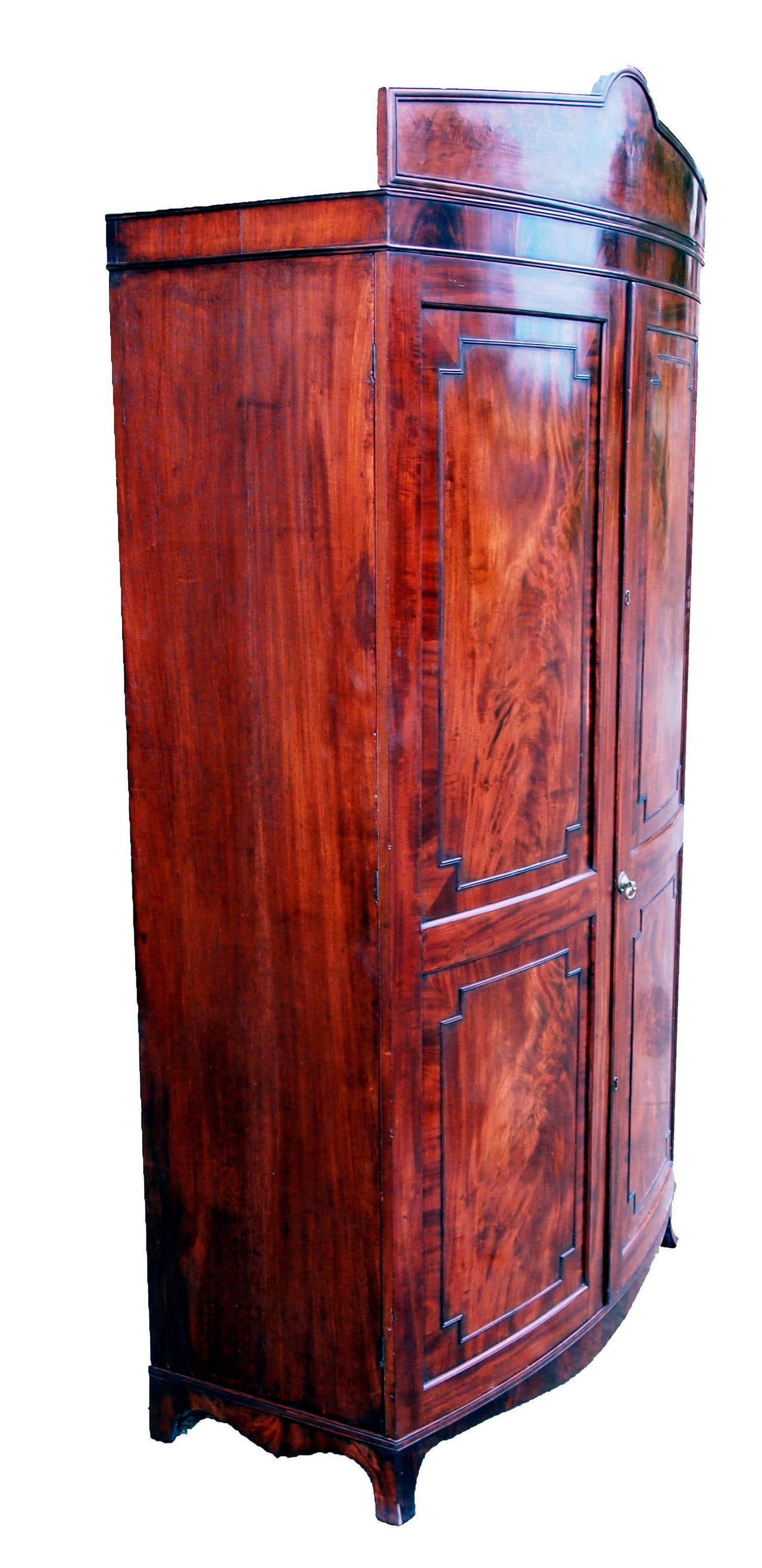 A delightful and rare Regency period mahogany bowfronted
wardrobe having two superbly figured panel doors standing
on original spay feet.