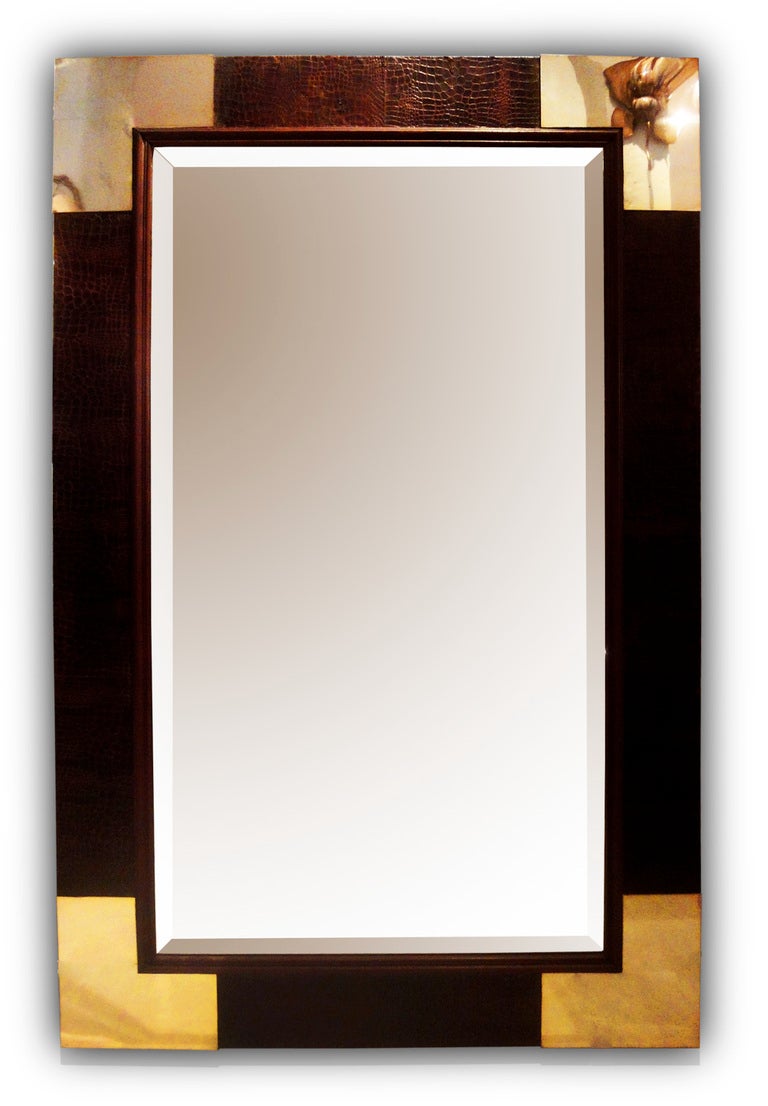 A rectangular wooden mirror covered in faux-crocodile with silvered-metal corners.