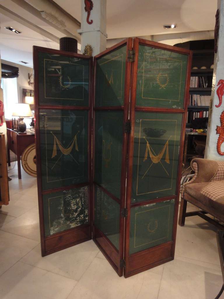 A three-leaf mahogany screen and painted-glass panels, decorated with cut-out Neoclassical figures. France. 1940’s. 
each leaf Measurements: 16.9 + 18.8 + 16.9 = 52.7 inches.