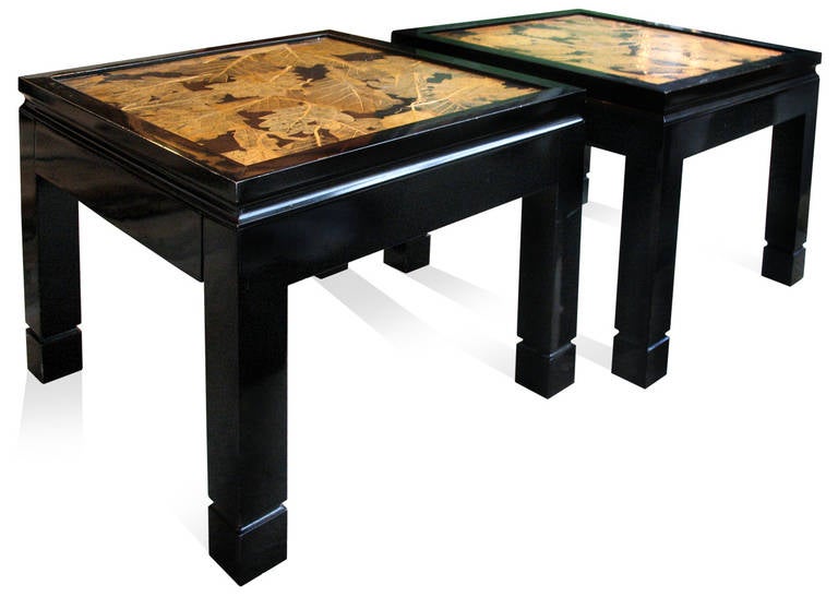 A pair of small side tables with black lacquered wood and tops decorated with a collage of oak-leaves.