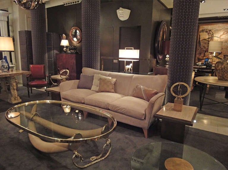 A large oval-shaped coffee-table with its base formed by two resine elephant tusks mounted on bronze rope and tassels.